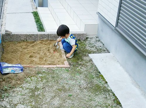 玄関のサイドには、小さな庭が広がっている。ボール遊びなどをする際に活用している他、一部をレンガで囲って砂場を作った。「公園が徒歩圏内にないため、家で砂遊びができるようにホームセンターで材料を揃えました。息子が喜んで使っています」