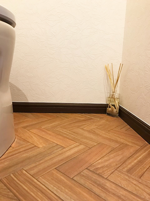 トイレの床はヘリンボーン調をセレクト。壁には葉の模様が入ったクロスを貼り、落ち着いた中に個性が感じられる空間をデザイン